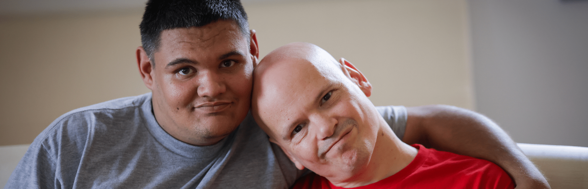 Two men smiling and the one on the left has his arm about the other.